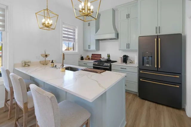 a kitchen with stainless steel appliances a sink a stove a refrigerator cabinets and a chandelier