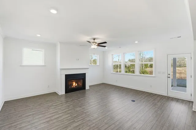 an empty room with wooden floor fireplace and windows