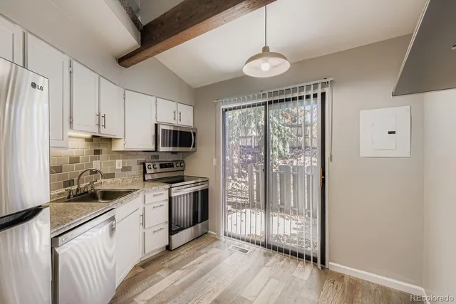 a kitchen with stainless steel appliances granite countertop a stove top oven a refrigerator a sink and dishwasher with wooden floor