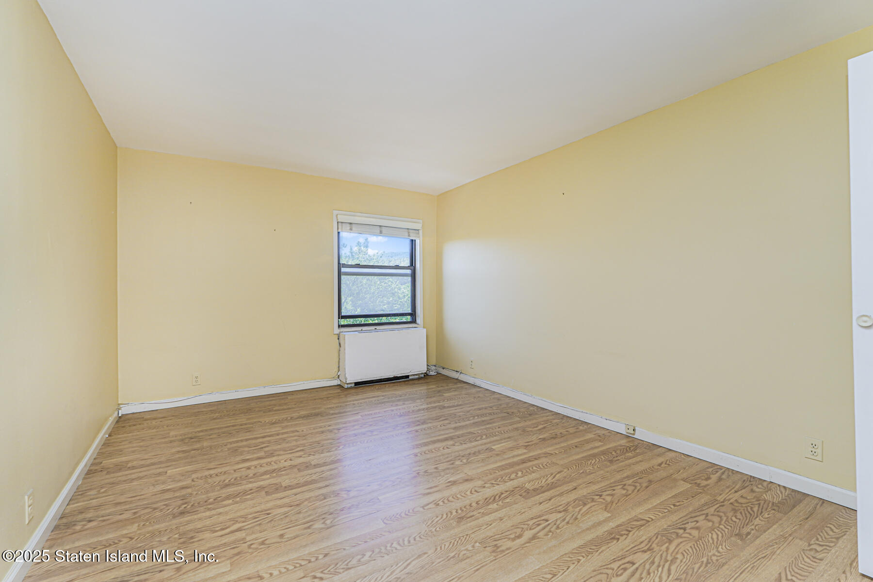 1100 Clove Road, Unit 60 Staten Island, NY 10301 - Photo 25 of 25 a view of an empty room with wooden floor and a window