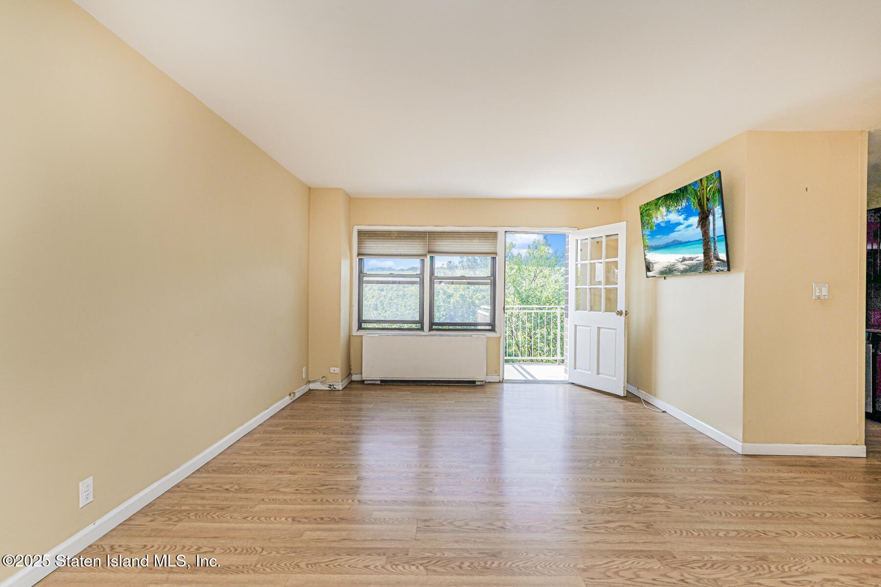 1100 Clove Road, Unit 60 Staten Island, NY 10301 - Photo 5 of 25 a view of an empty room with wooden floor and a window
