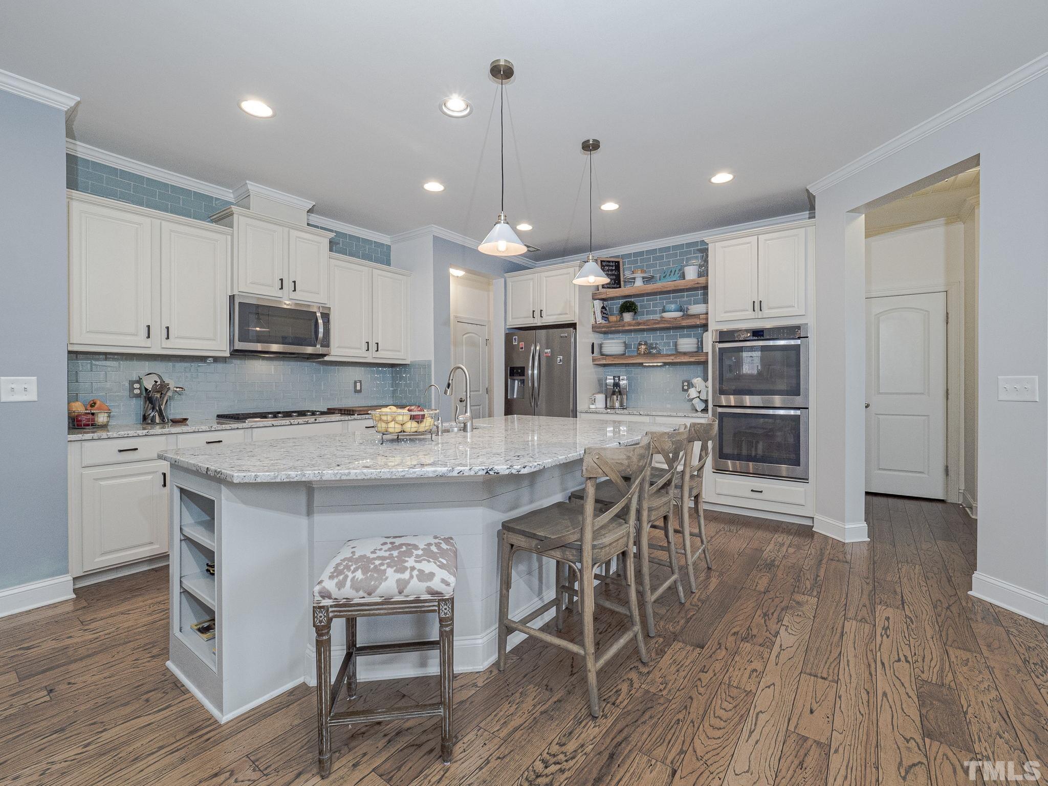 1990 Mostyn Lane Apex, NC 27502 - Photo 12 of 41 a kitchen with stainless steel appliances granite countertop a stove top oven a refrigerator a sink and a dining table with wooden floor
