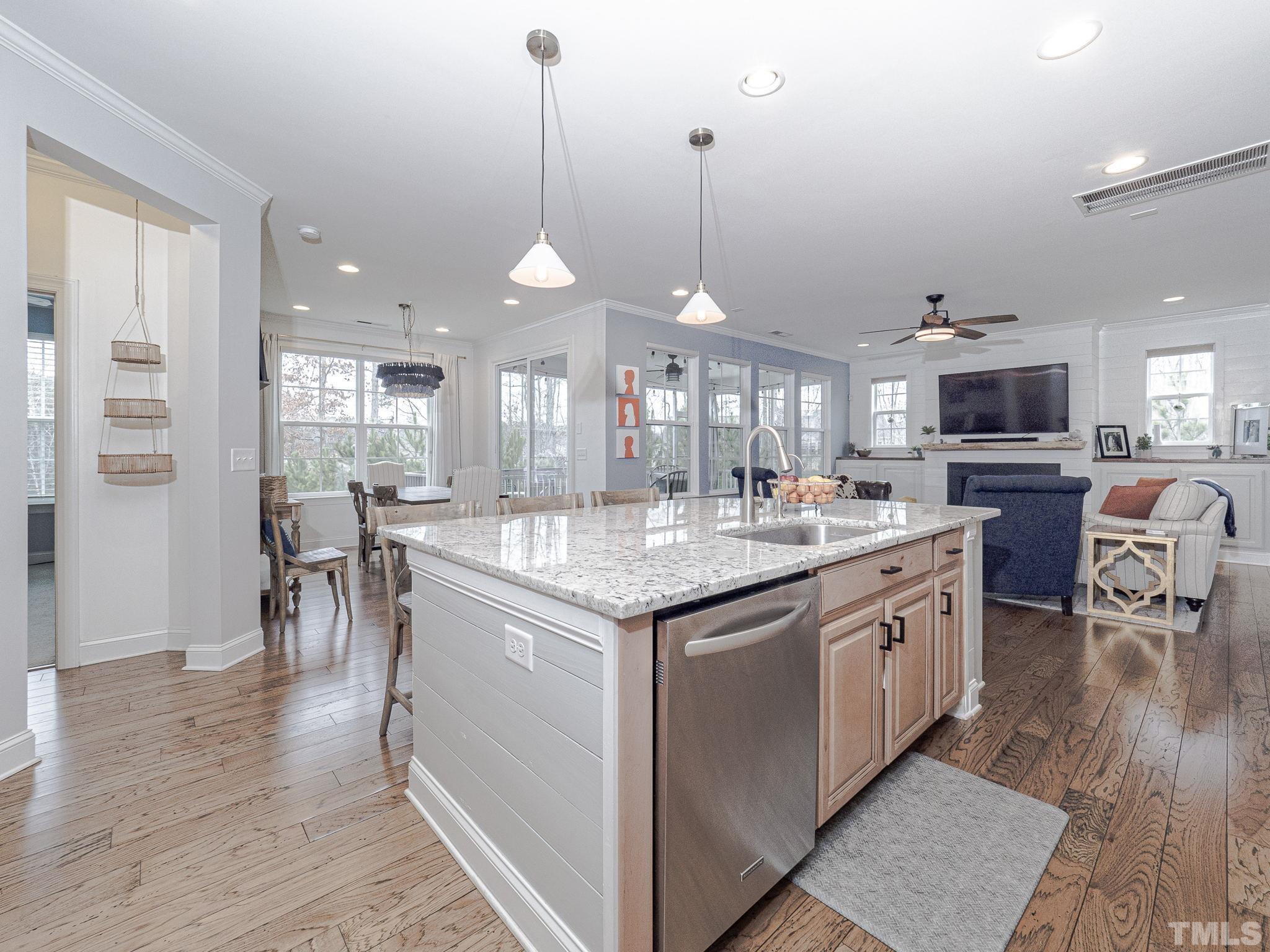1990 Mostyn Lane Apex, NC 27502 - Photo 20 of 41 a kitchen with stainless steel appliances granite countertop a stove top oven a sink dishwasher a dining table and chairs with wooden floor