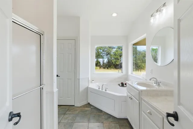a bathroom with a tub sink and mirror