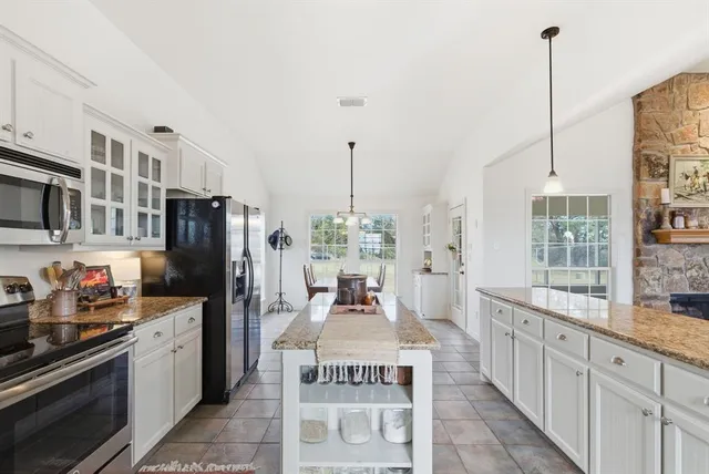 a kitchen with stainless steel appliances kitchen island granite countertop a refrigerator a stove and a wooden floors