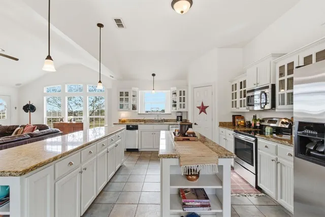 a large kitchen with stainless steel appliances kitchen island granite countertop a large counter top a stove a chimney and a center island