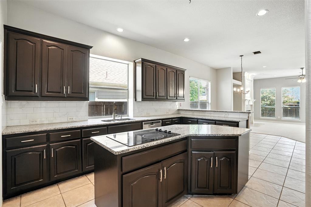8220 Holliday Road Lantana, TX 76226 - Photo 13 of 40 Kitchen featuring dark wood cabinetry, light-colored countertops, a tile backsplash, and a built-in cooktop island