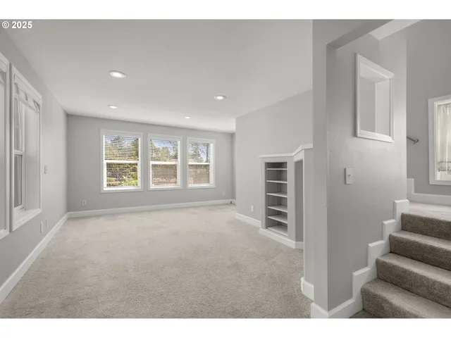 a view of an empty room with stairs and windows