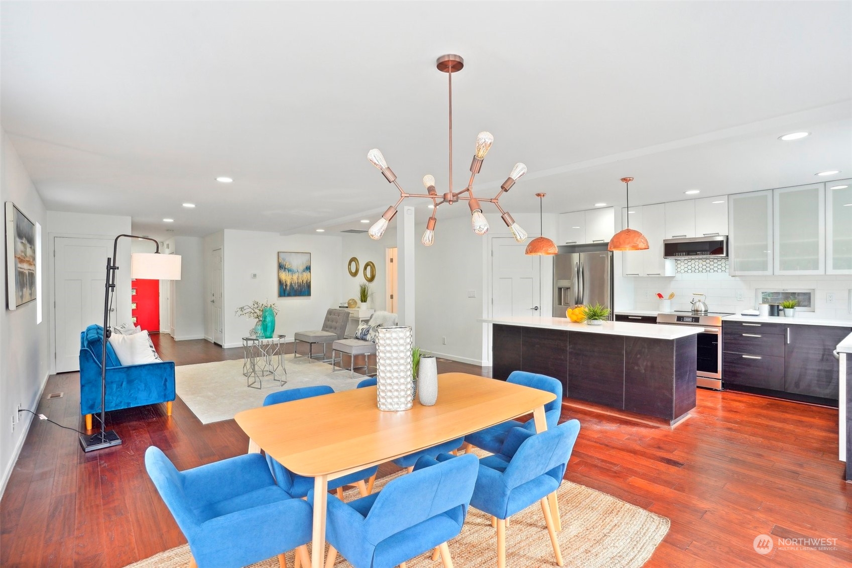 7453 Gatewood Road Southwest Seattle, WA 98136 - Photo 8 of 40 a large kitchen with stainless steel appliances kitchen island granite countertop a dining table chairs and a wooden floor