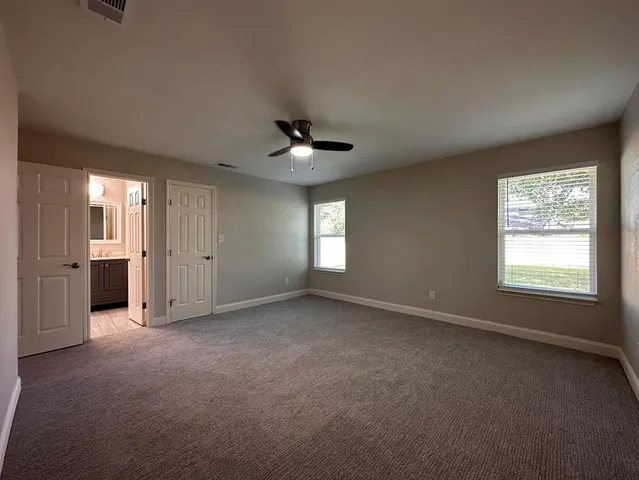 an empty room with windows and ceiling fan