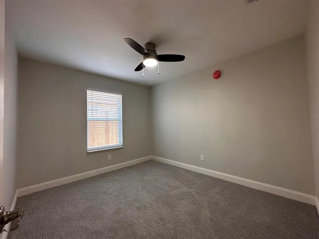 an empty room with ceiling fan and window