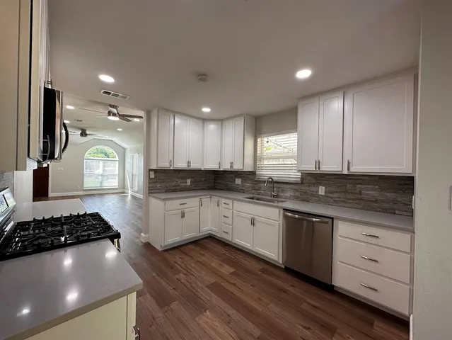 a kitchen with stainless steel appliances granite countertop a stove a sink and a microwave