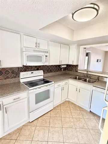 a kitchen with granite countertop white cabinets and white appliances