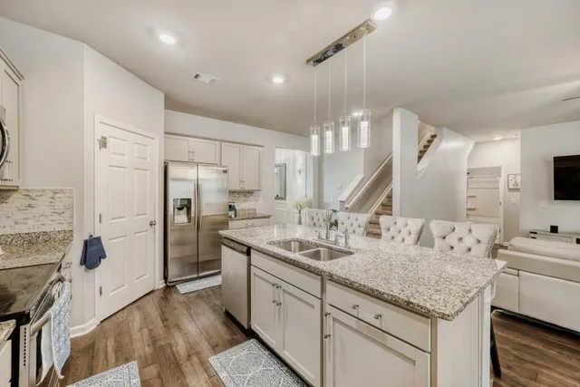 a kitchen with granite countertop a sink stainless steel appliances and white cabinets