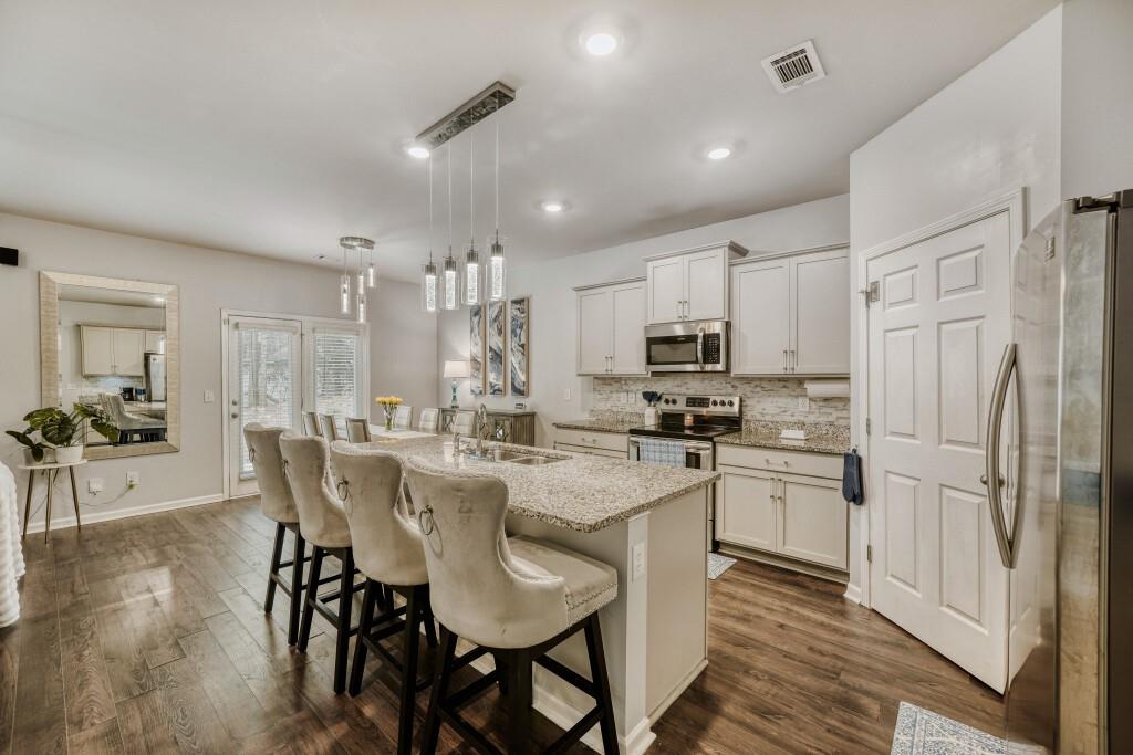 1526 Woodvale Street Hampton, GA 30228 - Photo 12 of 31 a kitchen with stainless steel appliances granite countertop a dining table chairs stove refrigerator and cabinets