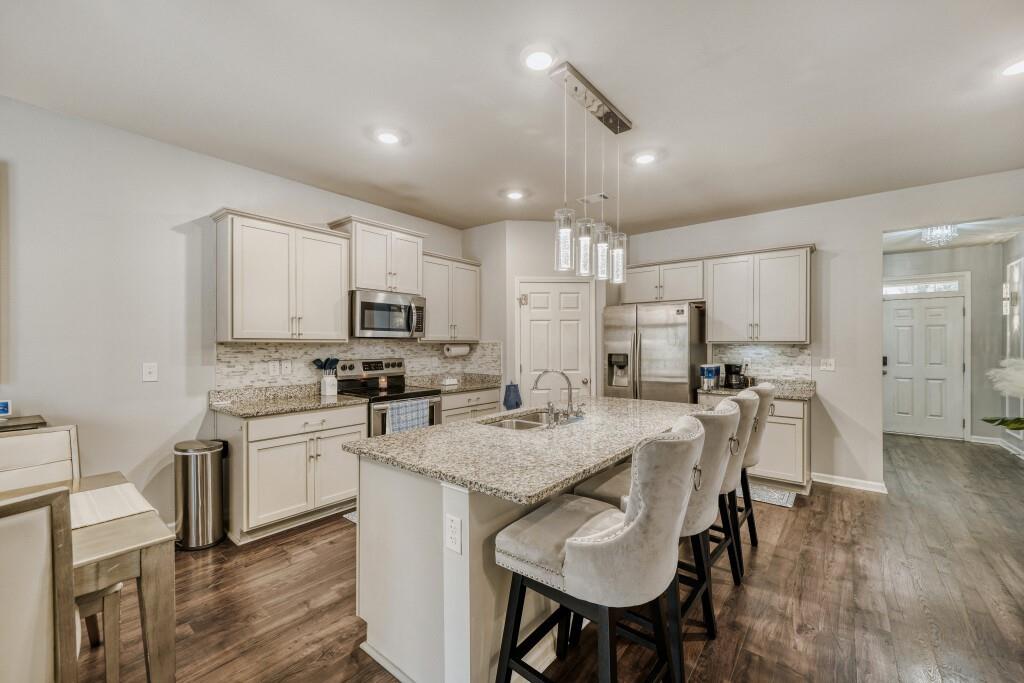 1526 Woodvale Street Hampton, GA 30228 - Photo 13 of 31 a kitchen with stainless steel appliances granite countertop a table chairs sink refrigerator and microwave