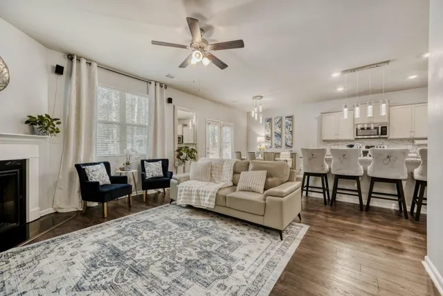 a living room with furniture kitchen view and a wooden floor
