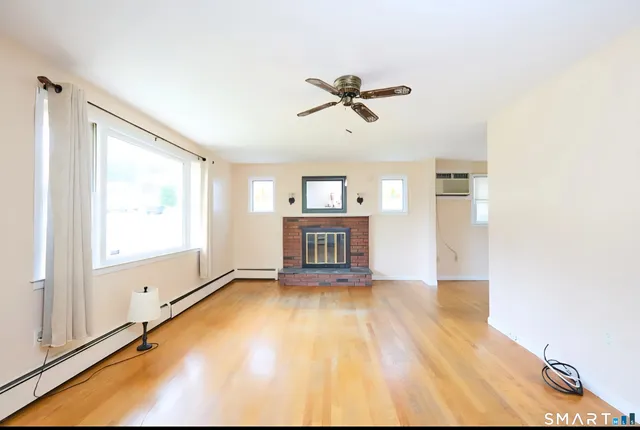 a view of an empty room with a window and wooden floor