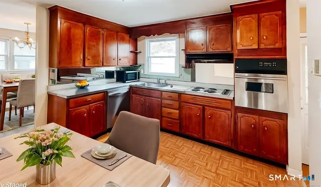 a kitchen with stainless steel appliances granite countertop a stove a sink dishwasher and cabinets with wooden floor