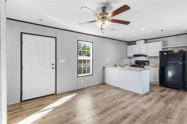 an empty room with wooden floor closet and windows