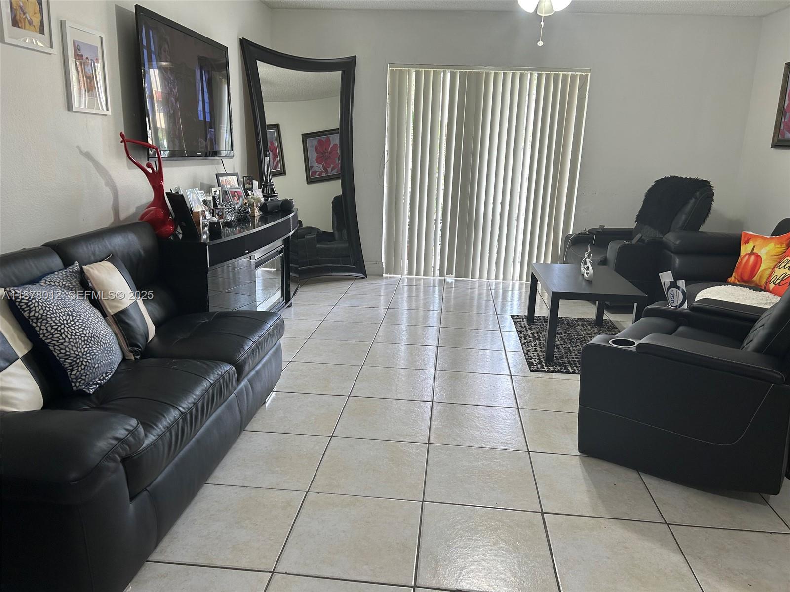 17901 Northwest 68th Avenue, Unit T101 Hialeah, FL 33015 - Photo 3 of 45 a living room with furniture and a flat screen tv