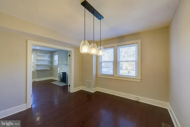 a view of an empty room with window and wooden floor