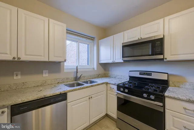 a kitchen with granite countertop white cabinets and stainless steel appliances