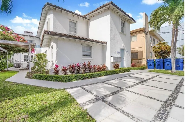 a front view of a house with a yard and potted plants