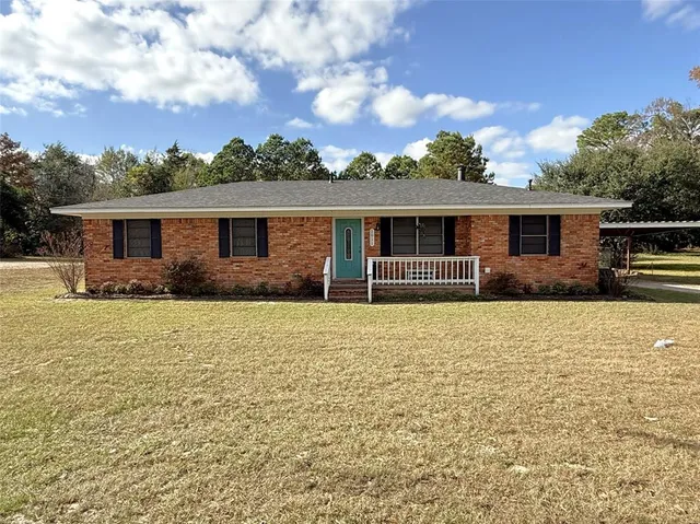 a front view of house with yard and trees in the background