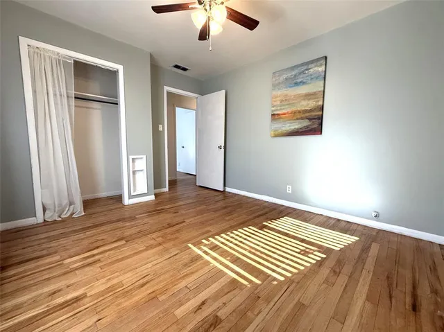 a view of a room with wooden floor and ceiling fan
