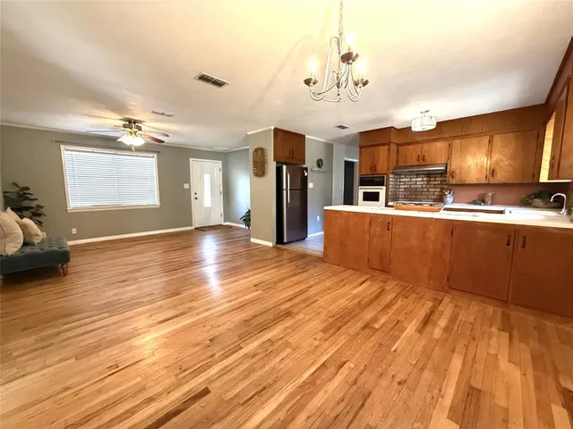 a view of a kitchen with kitchen island stainless steel appliances wooden floor and living room view