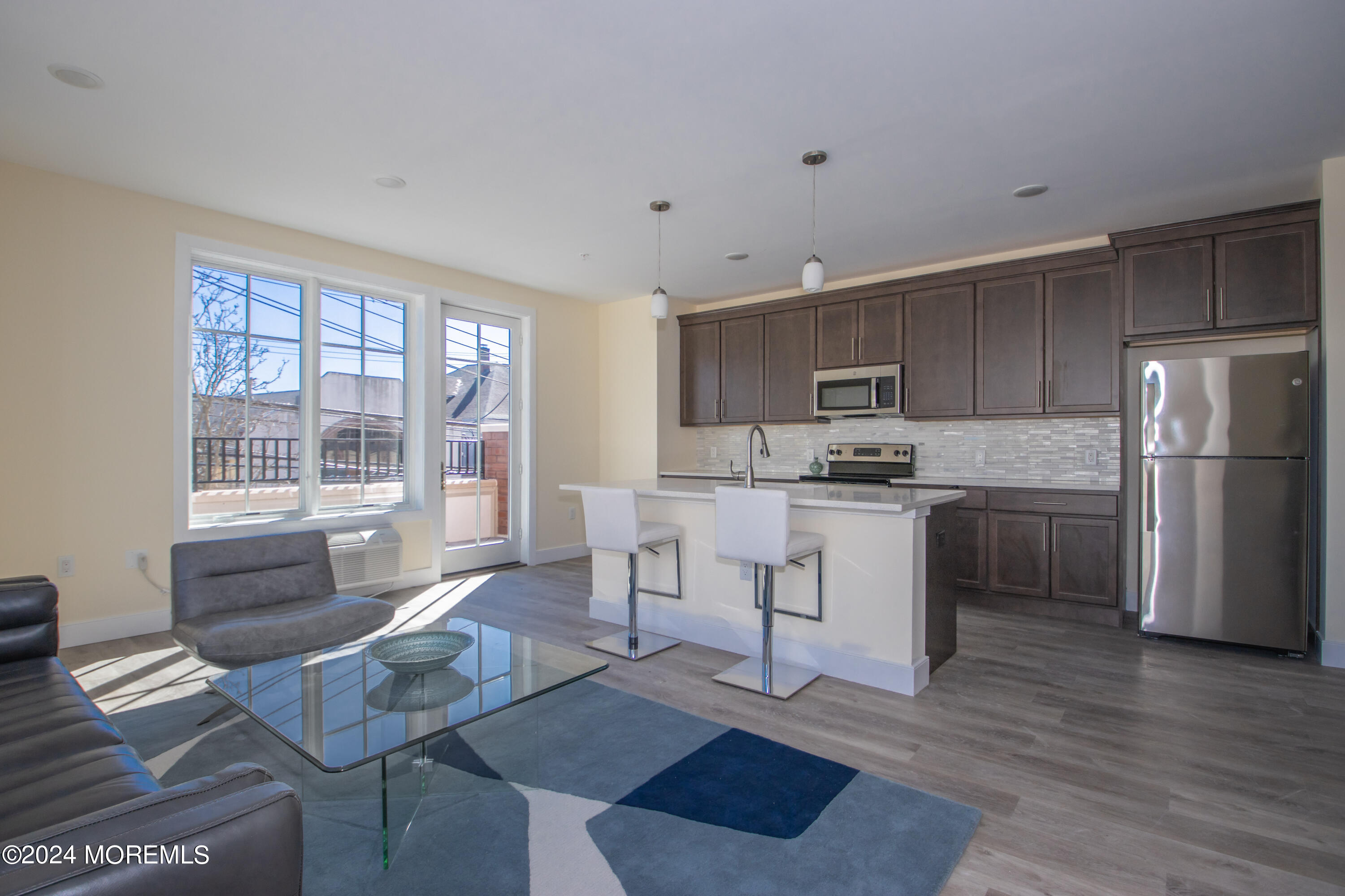 126 Main Street, Unit 410 Matawan, NJ 07747 - Photo 2 of 13 a kitchen with stainless steel appliances granite countertop a stove a refrigerator a sink a dining table and chairs with wooden floor