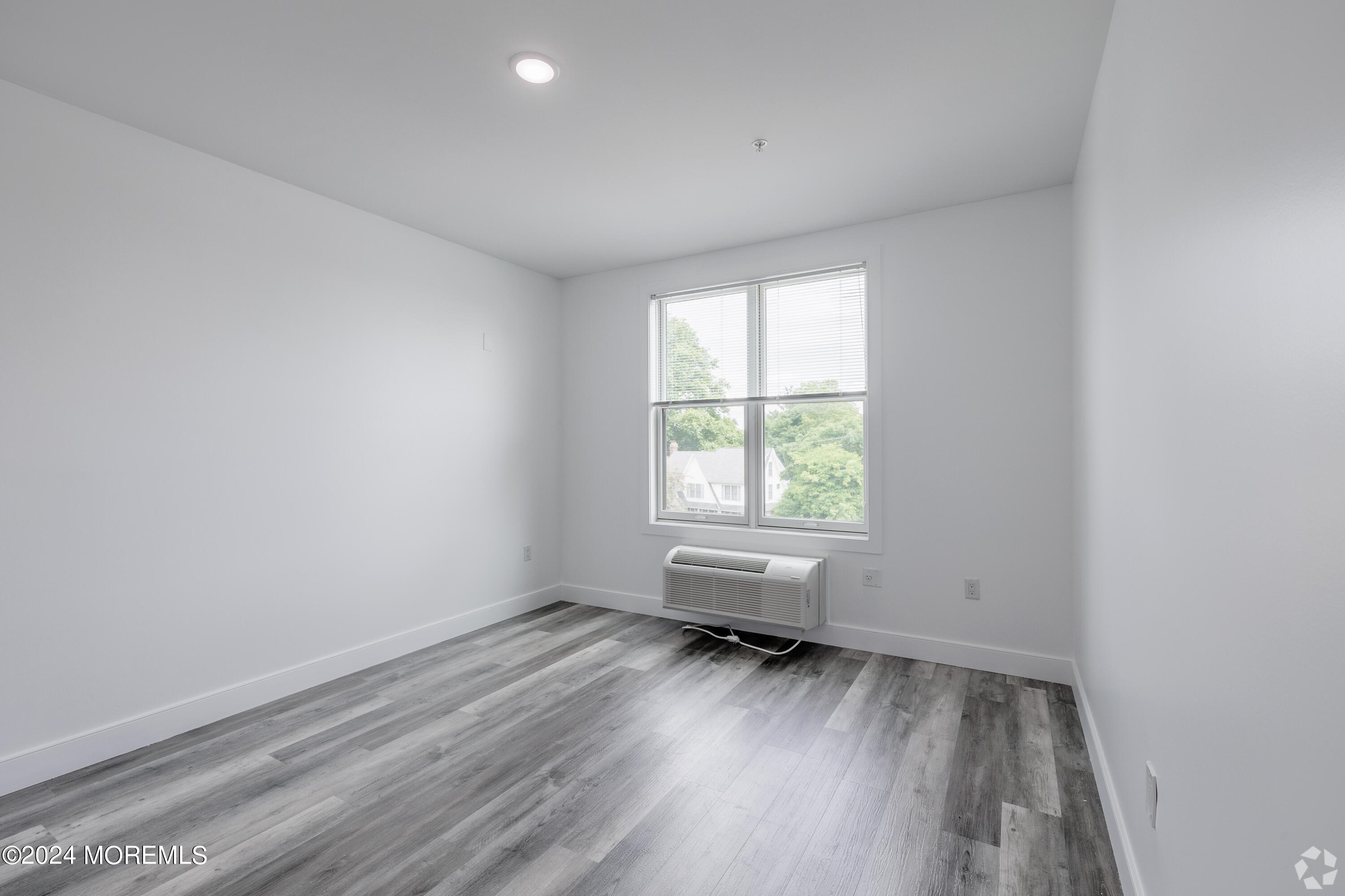 126 Main Street, Unit 410 Matawan, NJ 07747 - Photo 8 of 13 an empty room with wooden floor and windows