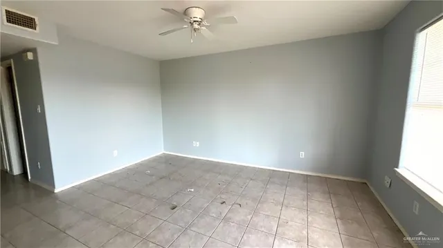 an empty room with windows and chandelier fan