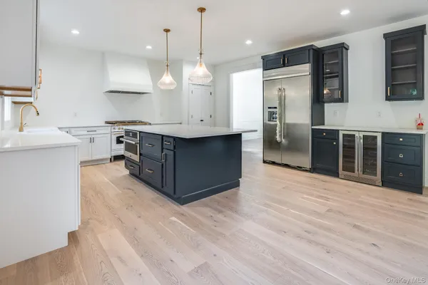 a large kitchen with stainless steel appliances a large counter top a sink refrigerator and cabinets