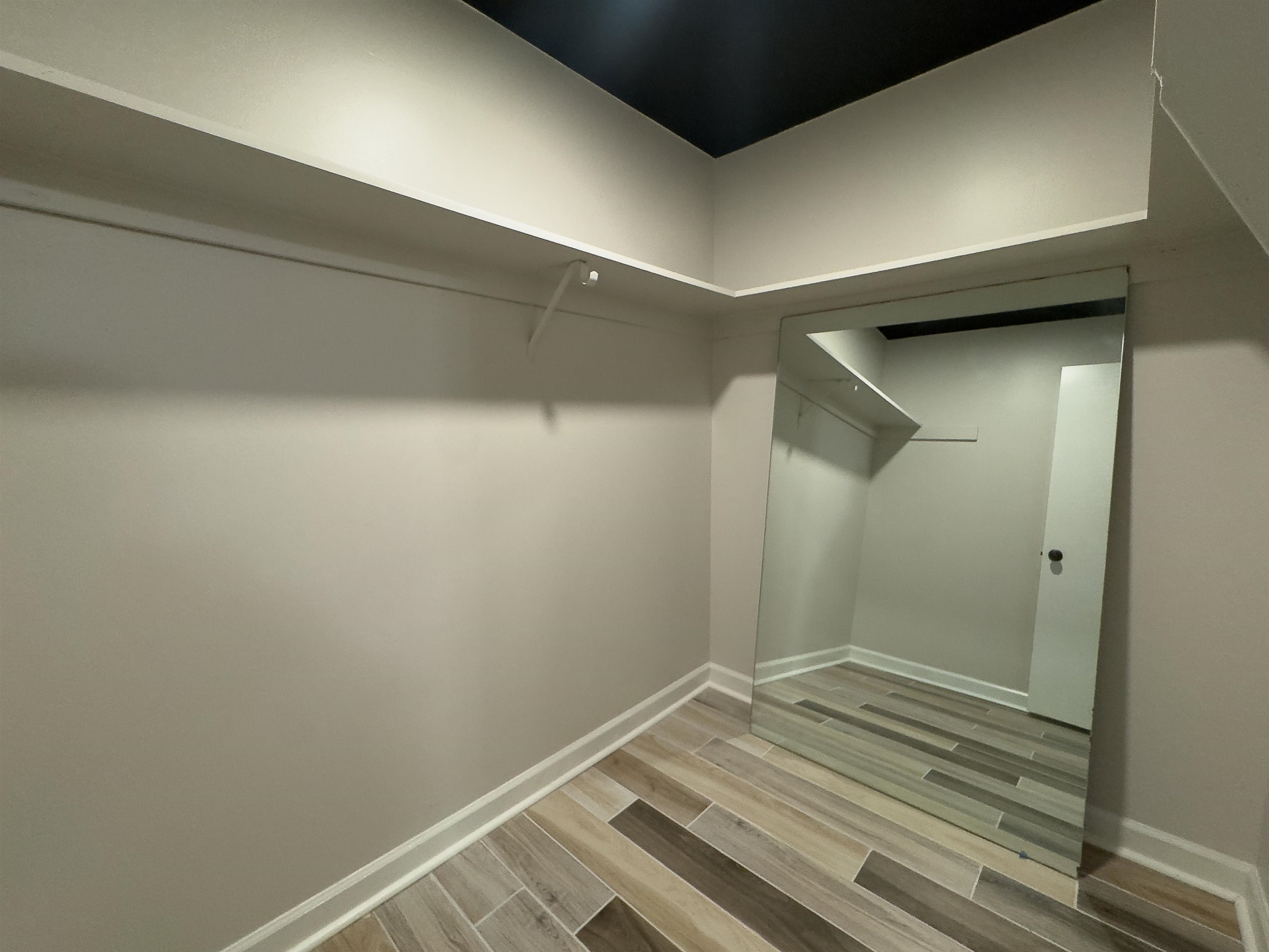 109 North Main Street, Unit 907 Memphis, TN 38103 - Photo 14 of 29 Corner closet featuring an integrated full-length mirror, wood-finish flooring, white baseboards, and built-in shelving with a hanging rod