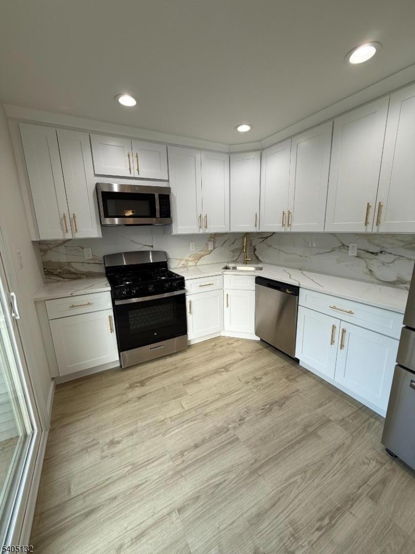 4202 Winder Drive Bridgewater, NJ 08807 - Photo 11 of 26 a kitchen with granite countertop a stove top oven a sink dishwasher and a microwave oven on the kitchen countertops with wooden floor