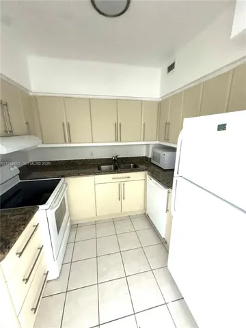 a kitchen with a sink a stove top oven and white cabinets