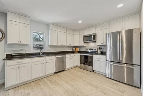 a kitchen with granite countertop a refrigerator stove top oven and sink