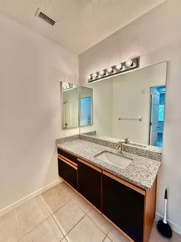 a bathroom with a granite countertop sink and a mirror
