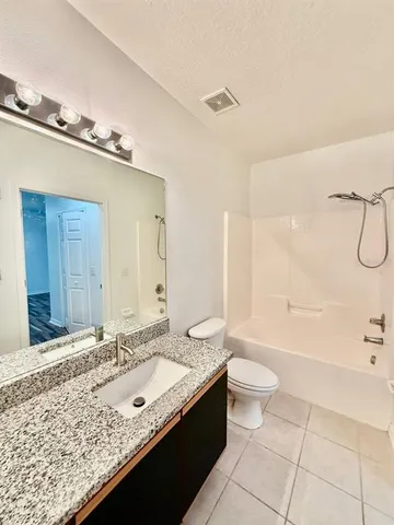 a bathroom with a granite countertop sink a toilet and shower