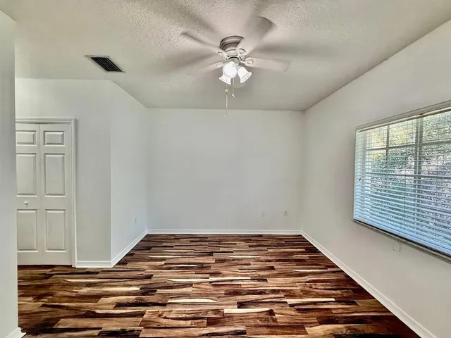 a view of a room with wooden floor and ceiling fan