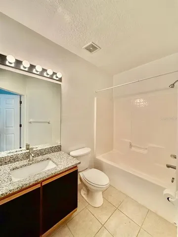 a bathroom with a granite countertop sink toilet mirror and bathtub