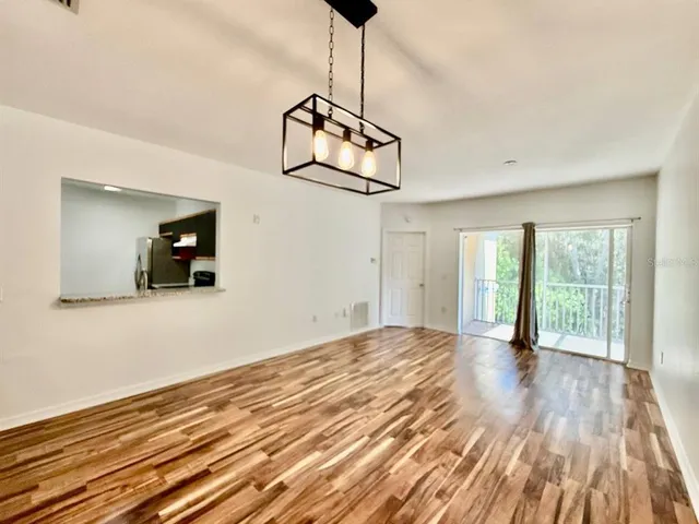 a view of empty room with wooden floor and fan