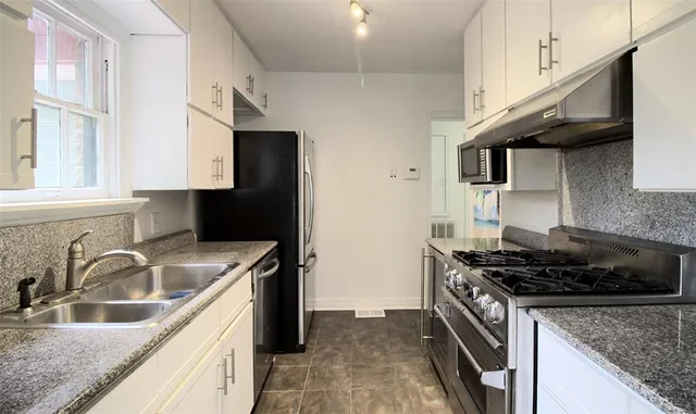 a kitchen with stainless steel appliances granite countertop a sink a stove and a microwave