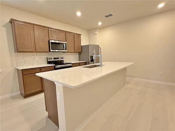 a kitchen with stainless steel appliances a sink a stove a microwave a sink a refrigerator and cabinets