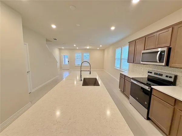 a kitchen with stainless steel appliances a stove top oven a sink and a refrigerator