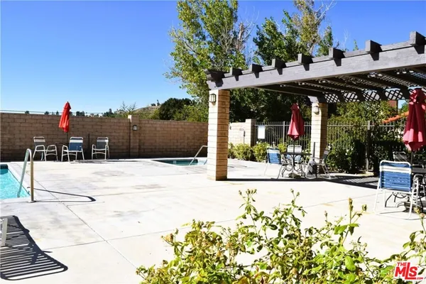 a view of a patio with table and chairs under an umbrella with large trees