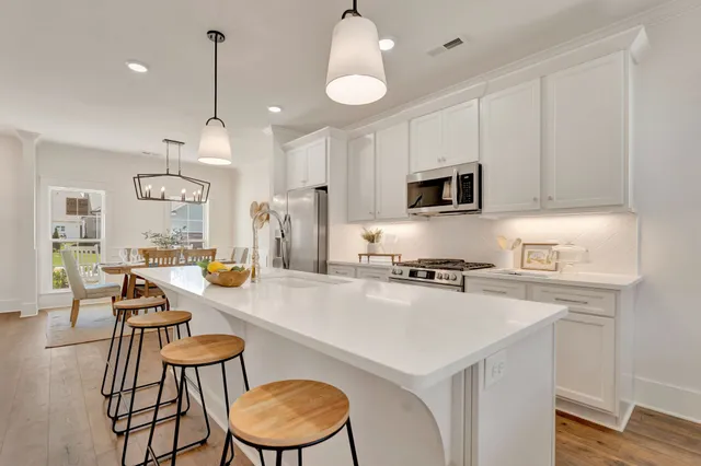 a kitchen with stainless steel appliances granite countertop a refrigerator a stove a sink dishwasher a oven a dining table and chairs with wooden floor