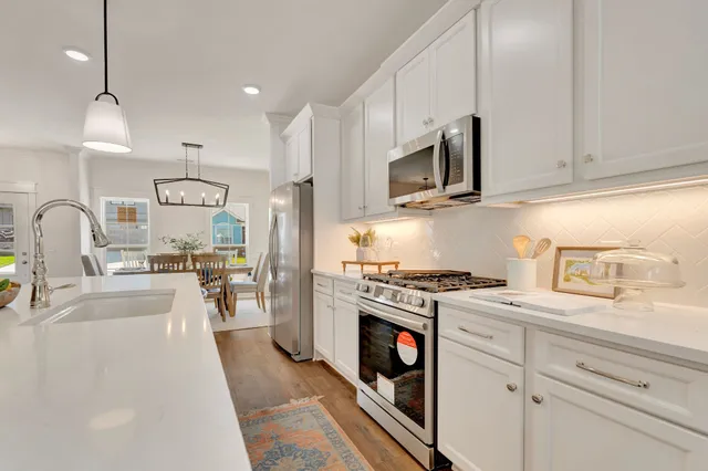 a kitchen with stainless steel appliances granite countertop a sink a stove and a wooden floors
